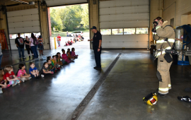 Fire fighter in gear in front of children