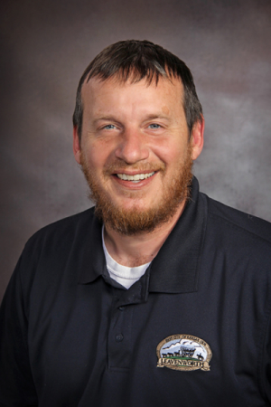 Photo of man with brown hair and beard in black polo shirt