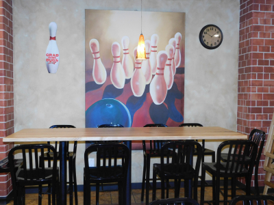 Table and chairs in the snack bar under an image of bowling pins.