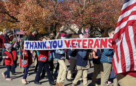 Children carry banner in Veterans Day parade that reads, "Thank You Veterans"