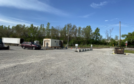 Entrance to the Leavenworth Brush Site, several piles of brush and yard waste on a gravel lot with a trailer office and vehicles