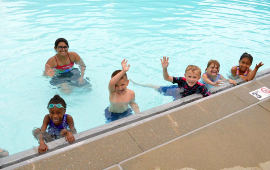 photo of children waving at a pool, text reads Wollman Aquatic Center 1300 Shawnee Open swim weekdays 1-7:30 p.m.