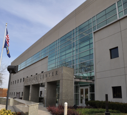 Photo of building with American flag, sign reads Justice Center