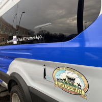 Photo of Ford Transit 350 van in blue and white with "RideLV" logo, City of Leavenworth logo and The Guidance Center logo