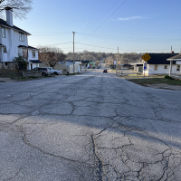 Photo shows road with cracks and uneven driving surface along Seventh Street near Seneca Street