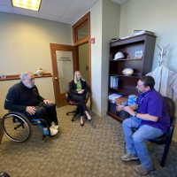 Man in wheelchair visits city staff inside city offices to talk about accessibility issues.
