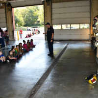 Fire fighter in gear in front of children