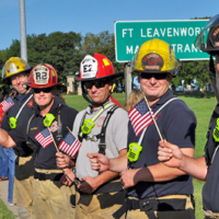 Firefighters wave American flags along the highway