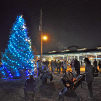 family by the lighted mayor's tree outside at Haymarket Square