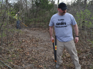 man with hedge trimmers working on the path wearing a shirt that says trail mob