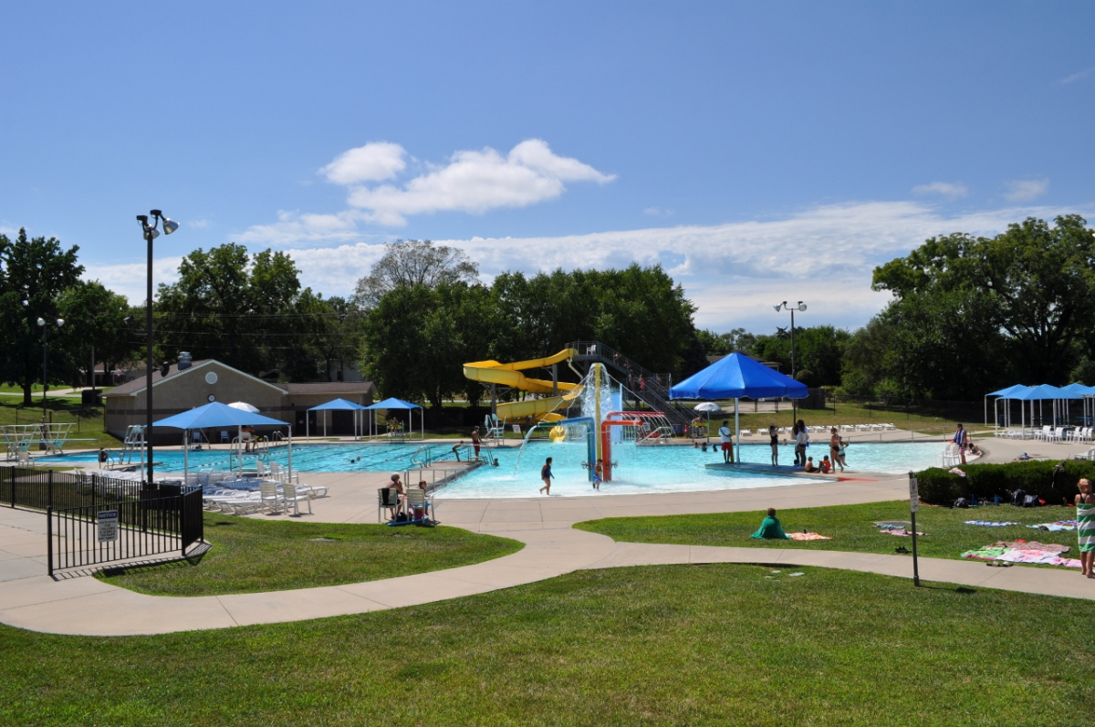photo of pool with zero depth entry surrounded by green grass and sidewalks
